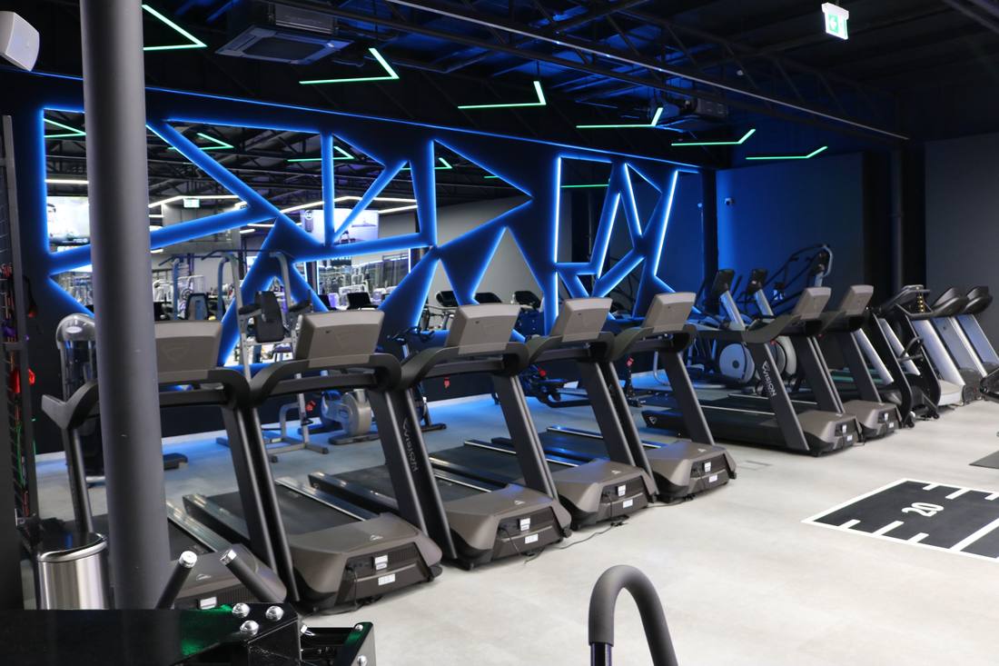 Treadmills in front of a blue lit wall